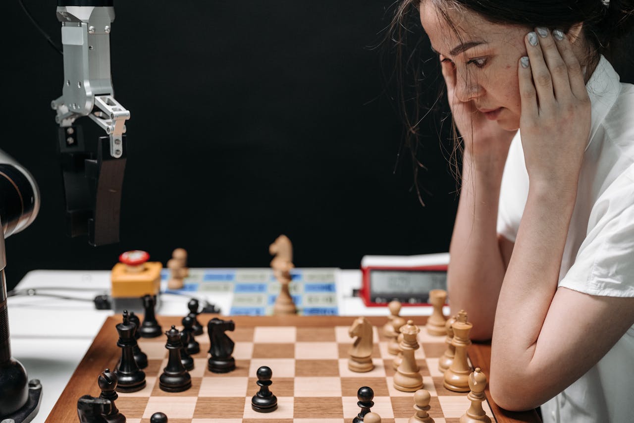 why-choose-us A woman engaged in a thought-provoking chess game with a robotic opponent.